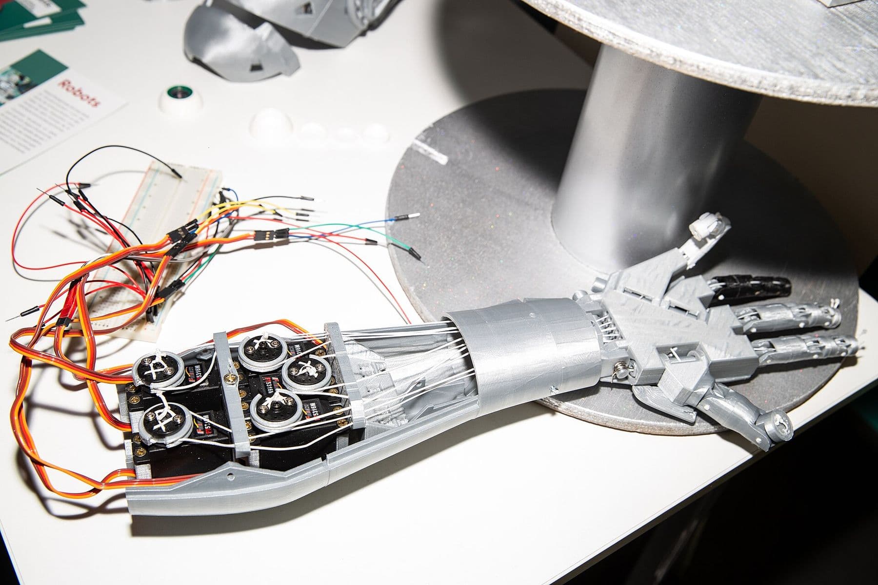 Robotic hand with exposed servo motors and wiring on a display table